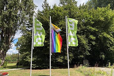Die inter*-inklusive Progress-Pride-Flagge zwischen zwei HTW-Flaggen am Campus Treskowallee © HTW Berlin/Anja Schuster