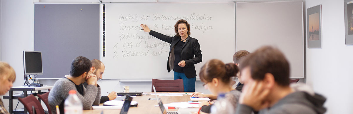 Professorin erklärt im Unterricht etwas an der Tafel